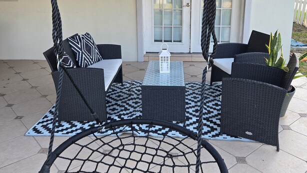 A covered patio with wicker furniture, a hanging swing, and a door with glass panels. - 5BR retreat/Sleeps large groups/Spacious backyard/Near South Padre and Space X. (Brownsville)