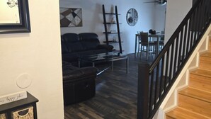 A living room with a sofa, a coffee table, a fireplace, and a staircase. - 5BR retreat/Sleeps large groups/Spacious backyard/Near South Padre and Space X. (Brownsville)