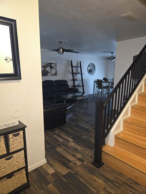 Ein Wohnzimmer mit Sofa, Couchtisch, Kamin und Treppe.