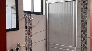 A bathroom with a white sink, a toilet, a shower with a glass door, and a mirror above the sink.