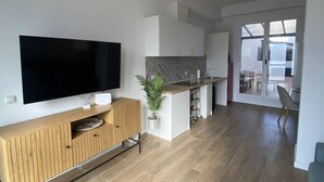 A modern kitchen with a flat-screen TV, wooden cabinetry, and a central island. - Travel Habitat Bioparc with Terrace Apartment A (Valencia)