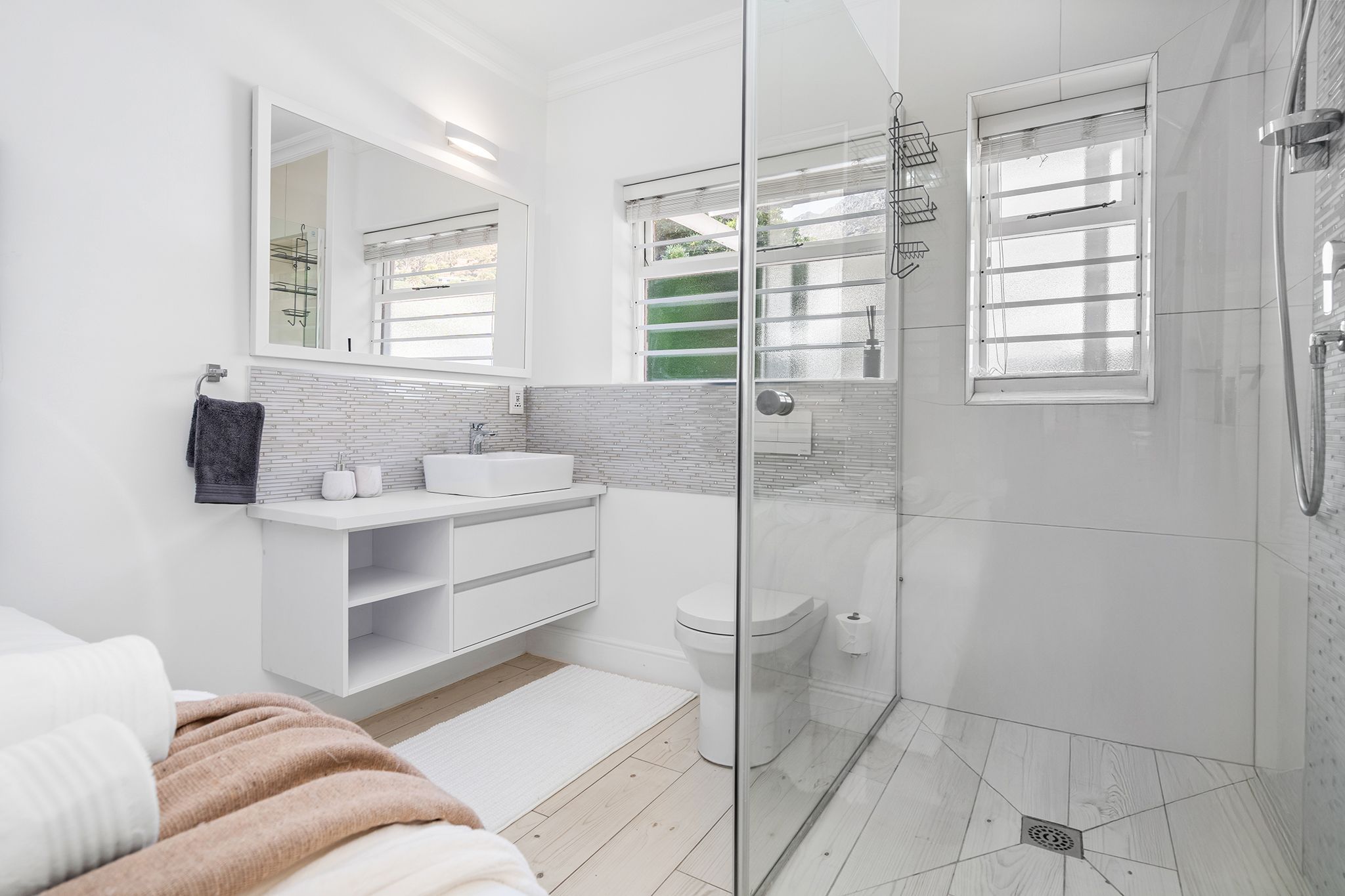 A modern bathroom with a glass shower enclosure, a white sink, and a large mirror.