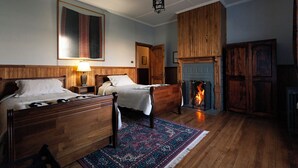 Ein traditionell eingerichteter Raum mit zwei Holzbetten, einem Kamin und einem großen Teppich.