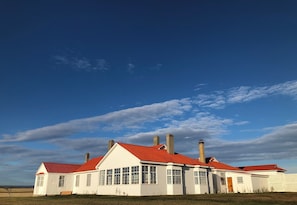 Un bâtiment blanc avec un toit rouge et de nombreuses cheminées.