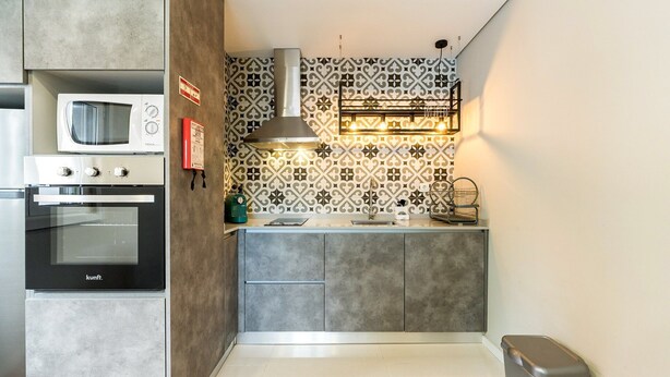 A compact kitchen with a microwave, oven, and modern backsplash.