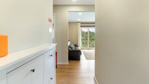 A hallway with a white counter, a fire extinguisher, and a sofa in a room with a large window.