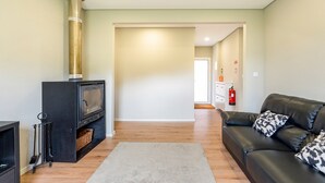 A living room with a fireplace, a sofa, and a hallway leading to another room.