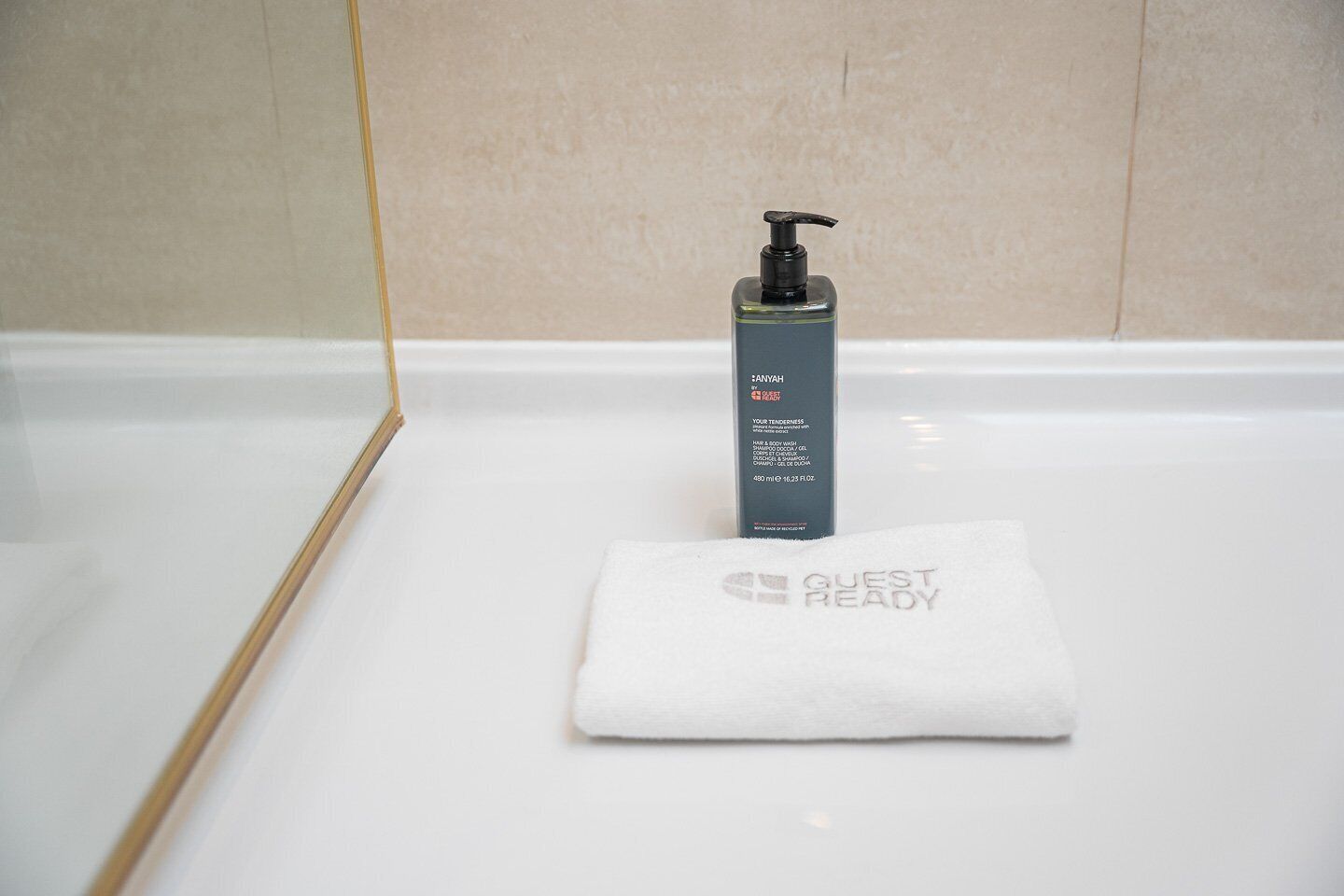 Et badeværelse med en hvid vask, shampoo og et håndklæde med teksten 'GUEST READY'.