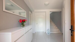 A hallway with a white reception desk, a vase of flowers, a mirror, and a staircase leading to another room. - Vacation home Bozena with pool (Donji Vinjani)