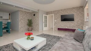 A living room with a sofa, coffee table, TV, and a potted plant. - Vacation home Bozena with pool (Donji Vinjani)
