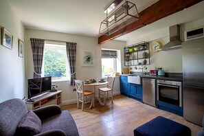 Un espace de vie compact comprenant un coin repas, une kitchenette et un téléviseur.