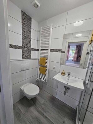 A modern bathroom with a toilet, sink, and towel rack.