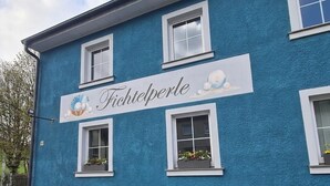 A building with a sign reading 'Fichitelperle' and windows with flower boxes. - Vacation apartment with several living units (up to 20 people) (Wunsiedel)