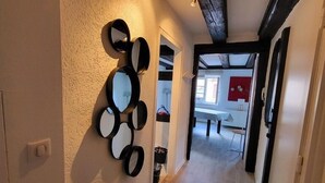 Un couloir doté d’un plancher en bois, d’un ensemble de miroirs fixés au mur et d’une porte donnant sur une autre pièce.