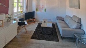 Un salon avec un canapé, un téléviseur, une table basse et une fenêtre donnant sur un beau paysage.