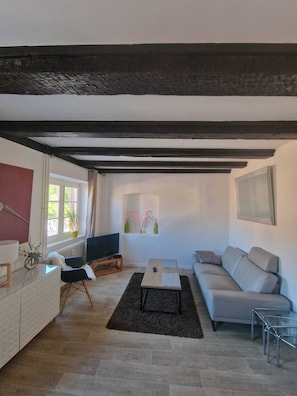Ein Wohnzimmer mit einer Couch, einem Fernseher, einem Couchtisch und einem Fenster mit Blick.