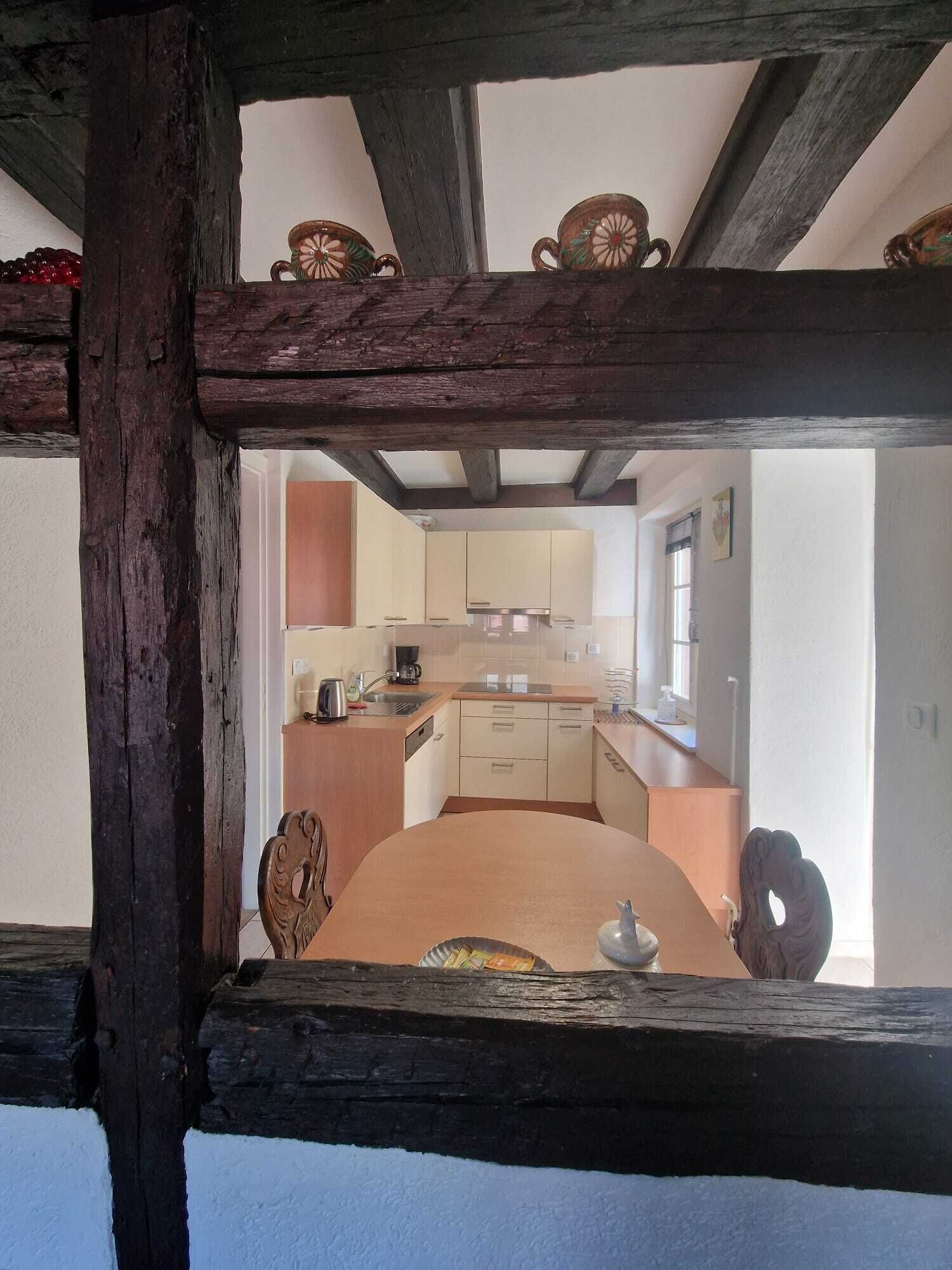 Une cuisine rustique avec des poutres en bois, un îlot central et une vue encadrée par une structure en bois.