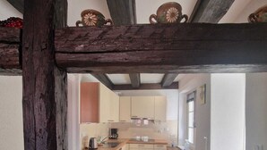 Une cuisine rustique avec des poutres en bois, un îlot central et une vue encadrée par une structure en bois.