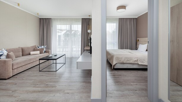 A modern hotel room with a sofa, a bed, a coffee table, and a view of the outside. - BelMare Aqua Resort 233 by Solarento (Międzyzdroje)