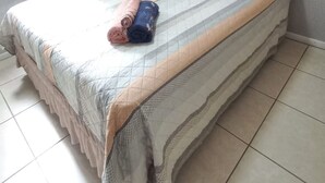 Uma cama com cabeceira estofada, edredom listrado e toalhas enroladas sobre a cama.