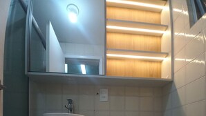 Casa de banho com lavatório, espelho e sanita.