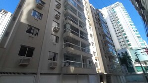 Um edifício com várias andares, varandas, janelas amplas e um céu claro.