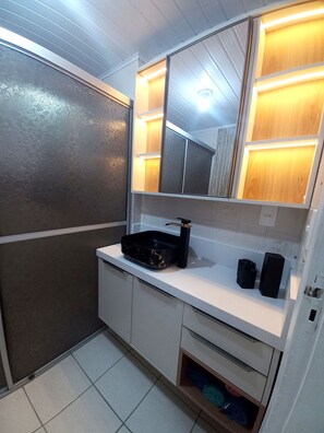 Un baño con un lavamanos tipo recipiente negro, un espejo y un perchero para toallas.