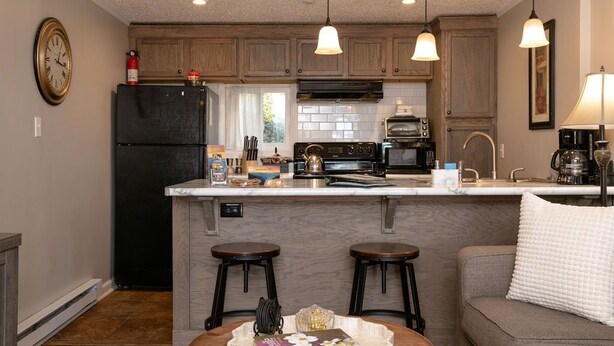 A kitchen with wooden cabinets, a black refrigerator, a central island with stools, and pendant lighting.