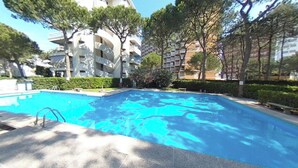A swimming pool with a diving board, surrounded by trees and multi-story buildings. - Beachfront Family Flat With Terrace (Lignano Sabbiadoro)