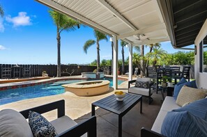 A covered outdoor area with a pool, lounge chairs, and a fire pit. - Limited July Availability | Luxury Pacific Beach Retreat with Pool, Spa & Endles (San Diego)