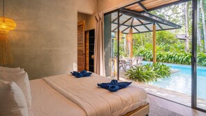 A bedroom with a bed, a window, and a view of an outdoor pool area.