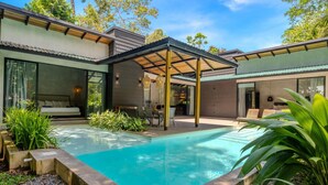 A modern house with a swimming pool, covered patio, and a dining area.