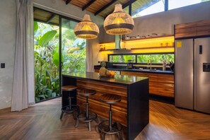 A modern kitchen with a central island, bar stools, and hanging pendant lights. - Hidden House: Luxury, Private Pool, 4WD Only (Punta Uva)