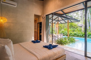 A bedroom with a large bed, a view of a swimming pool, and a glass door leading to an outdoor area.