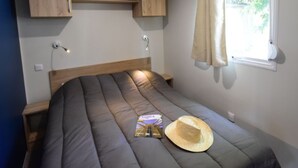 A bedroom with a bed, a window with curtains, a wall-mounted shelf, and a bedside lamp. - Cottage PARKS Sen Yan - Village Tropical (Mézos)