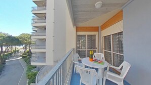 Un balcon avec une table et des chaises, une vue sur un immeuble doté de balcons et un ciel dégagé.