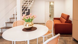 A dining area with a white table, a vase of pink flowers, and a red sofa. - Pachita Seaside Rooms (Polignano a Mare)