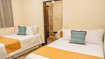 A room with two beds, a stone wall, and a wooden ceiling.