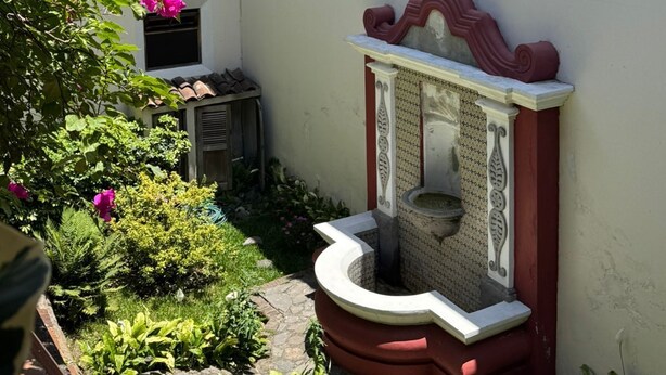 En innergård med en fontän, ett litet fönster och en mur som är täckt av murgröna.