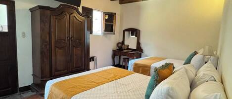 Un dormitorio con cama, vigas de madera en el techo, televisor, escritorio y espejo.