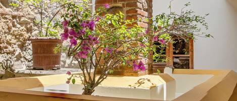 Un patio con una torre de ladrillo, plantas en macetas y un banco de madera.