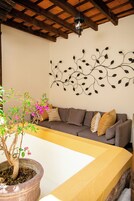 Un salón con sofá, decoración en la pared y una planta en maceta.