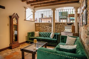 Uma sala de estar aconchegante com um sofá verde, uma mesa de centro de madeira e um grande relógio de pêndulo.