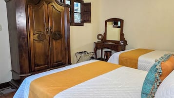 Habitación con dos camas, muebles de madera, televisión y piso de baldosas.