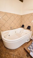 Una bañera blanca en un baño con piso y paredes de azulejos.