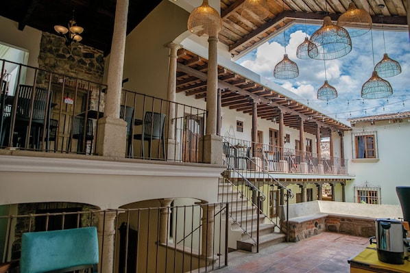Ein mehrgeschossiges Interieur mit einer Treppe, Holzbalken und hängenden Leuchten.