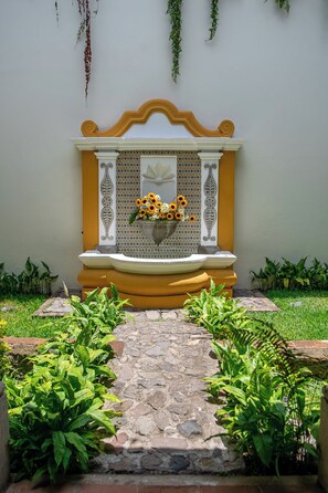 A stone pathway leading to a bench with a flower arrangement. - Hotel Casa Colonial by AHS (Antigua Guatemala)