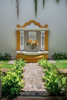 Un sendero de piedras que lleva a un banco con un arreglo floral.