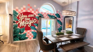 A dining area with a checkered wall mural, a round table with chairs, and a hanging light fixture. - The Sanctuary (Davenport)