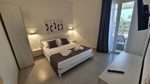Ein Hotelzimmer mit Bett, Nachttischen, Fernseher und Blick ins Freie.